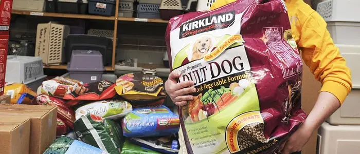 a woman holding a large bag of Kirkland dog food